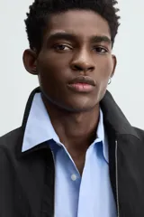 Sobrecamisa color crema de tejido técnico ligero, corte regular fit, cuello solapa, manga larga con puño abotonado, bajo ajustable con elástico en laterales y cierre frontal con cremallera.