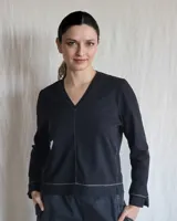 Remera blanca de mangas largas con cuello en V y costuras a la vista.