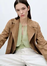 Blusa color verde claro de gasa semitransparente, con cuello redondo con lazos, mangas largas abullonadas con puños elásticos y diseño combinado.