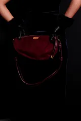 Cartera tipo sobre color bordó, confeccionada en PU tipo gamuza, con correa regulable de nudos chunky y cierre superior.