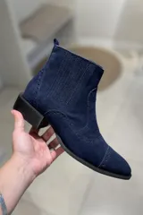 Bota corta de cuero vacuno color negro charol, con elástico lateral, punta fina y detalles de calado.