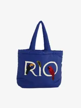 Bolso tote azul con asas cortas y bordado de la palabra "RIO" con un tucán, una hoja de palma y un guacamayo.