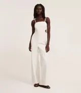 Mono largo color blanco, de breteles finos y escote recto. Presenta recorte cut-out en la cintura y lazo en la espalda.