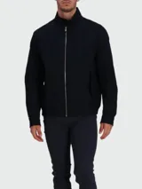 Chaqueta tipo bomber o Harrington de color azul oscuro, con cuello alto abotonado, cierre frontal de cremallera y pequeño logo bordado en el pecho.