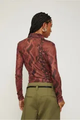 Body de poliéster y elastano con estampado de piel de serpiente en tonos marrones y negros. Tiene mangas largas, escote en V cruzado y calce ajustado al cuerpo.
