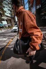 Bolso duffel negro de cuero sintético con logo de ancla bordado en rosa. Tiene doble asa de mano reforzada, correa de hombro regulable y desmontable, cierre superior con doble cremallera y tres bolsillos (dos exteriores y uno interior).