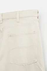Pantalón color marrón con efecto lavado, corte relaxed fit, cinco bolsillos, aplicación de tira y bolsillo multifunción en perneras, cierre frontal con cremallera y botón.