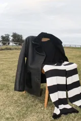 Gamulán negro de cuero genuino con cuello y solapas de piel sintética. Cierre frontal con botones y bolsillos de parche con ribete de piel sintética.