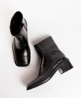 Botas cortas de cuero con estampado de piel de serpiente en tonos grises y negros. Tienen un tacón bloque de madera negro y cierre lateral con cremallera.