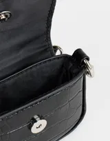 Monedero de cuerina color negro con textura croco, formato bolso con manija desmontable y solapa con broche con botón para cerrado.