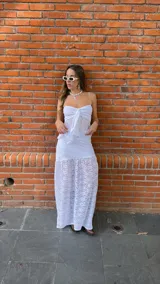 Pollera larga de encaje blanco con volados en el ruedo. Tiene un top a juego con breteles finos y volados en el busto, con un lazo en el centro.