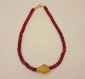 Collar de cuentas rojas con dije de piedra color ámbar.