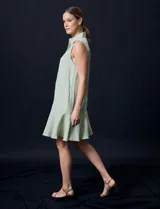 Vestido corto blanco de gasa, sin mangas, con cuello camisero, abertura central con botones y terminación de ruedo con volado.