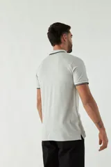 Remera tipo polo gris con cuello y mangas con ribete negro y logo bordado en el pecho.