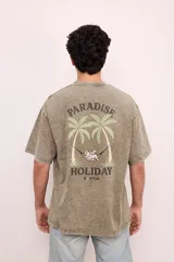 Remera negra con efecto gastado, corte oversize, mangas cortas y estampa en la espalda con palmeras, ángel en una hamaca y texto "Paradise Holiday Brixton".