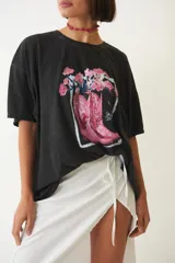 Remera negra holgada de manga corta con estampa de botas de cowboy rosas y flores.