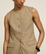 Short pollera de poliéster color beige, de corte sastrero, con cintura alta, pliegues delanteros y cintura lisa.