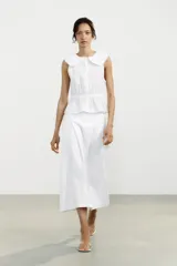 Falda midi blanca de tiro alto con pliegues y bolsillos laterales ocultos. Cierre lateral con cremallera oculta.