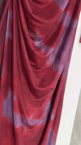 Vestido midi de microtul doble, color borgoña con estampado difuminado en tonos lila. Tiene cuello alto y mangas largas de una sola capa de microtul.