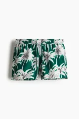 Short de baño verde con estampado de palmeras blancas y negras, cintura elástica con cordón ajustable, bolsillos laterales y trasero.
