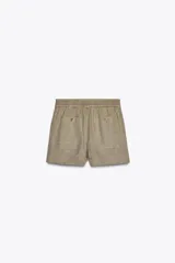 Shorts de tiro medio confeccionados en lino 100%. Cuentan con bolsillos laterales ocultos en la costura, bolsillos de parche en la parte trasera, cintura elástica, aberturas laterales en el bajo y cierre frontal con botones.