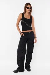 Pantalón cargo negro de corte recto y tiro bajo, con múltiples bolsillos laterales con tapa y botón a presión.