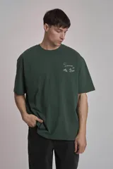 Remera verde oscuro de corte oversize con estampado pequeño en el frente.