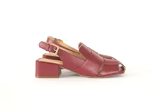 Sandalia de cuero color borgoña, con punta cuadrada y tiras anchas entrecruzadas. Tiene talón abierto con pulsera ajustable y hebilla metálica. El taco es ancho y mide 4 cm.