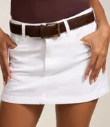 Minifalda blanca de sarga de algodón con trabillas en la cintura, cierre con botón y cremallera, y bolsillos delanteros y traseros.