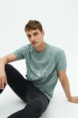Remera verde de manga corta con cuello redondo y estampado blanco con la leyenda 'Budapest Hungary' y un dibujo de un edificio.