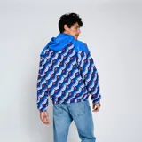 Campera deportiva Umbro Windbreaker del Club Nacional de Football. Diseño con paneles en azul y estampado geométrico en azul, rojo y blanco. Incluye capucha, cierre frontal y logo de Umbro y escudo del club en el pecho.