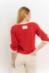 Sweater rojo tejido a mano con hilo, de corte holgado y cuello redondo. Presenta detalles en color crudo en el cuello, puños y ruedo.