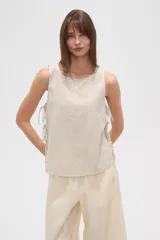 Blusa sin mangas con estampado a rayas verticales en tonos blanco, azul y verde. Presenta cuello redondo y lazos laterales.