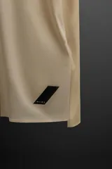 Remera deportiva marrón de tejido técnico, ligero y elástico con estructura perforada. Cuello redondo, manga corta, bajo asimétrico con aberturas laterales, costuras termofijadas y logo estampado.