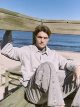 Polo de manga larga gris claro con cuello tipo camisa y cierre parcial con botones. Corte holgado y puños de canalé.