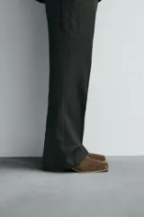 Botín de cuero negro con acabado serraje, cierre de cremallera lateral, horma cuadrada y tacón de 5 cm.