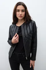 Chaqueta negra de eco cuero con cierre frontal y cuello redondo. Presenta paneles con diseño geométrico de tiras en relieve en el frente y mangas.