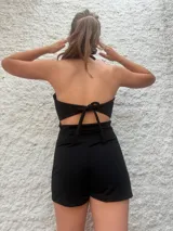 Mono corto negro con escote halter y falda cruzada.