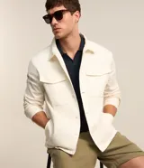 Campera trucker masculina de jeans color crudo, con cuello solapa, abotonado delantero, bolsillos con solapa y superficie lisa.