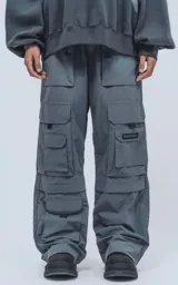 Pantalón cargo gris de corte oversize, confeccionado en tejido técnico de poliéster. Cuenta con cintura elástica, múltiples bolsillos y detalles reflectivos.