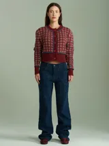 Cardigan de punto color borgoña con diseño geométrico en blanco y detalles en azul. Tiene cuello redondo, cierre frontal con botones rojos y mangas largas con puños acanalados.