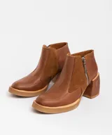 Botas cortas de cuero negro con textura de piel de serpiente, cierre lateral con cremallera, taco de madera forrado en cuero y punta fina.