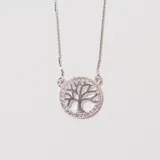Collar plateado con dije circular calado con forma de árbol de la vida y borde con pequeños cristales.