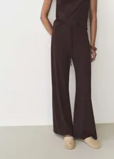 Pantalón largo de mujer color beige, de corte ancho y tiro alto, con cintura elástica y lazo ajustable.