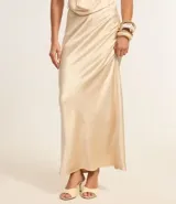 Vestido largo de satén color crema, con escote halter, espalda descubierta y abertura frontal. Presenta detalles de pedrería en el escote.