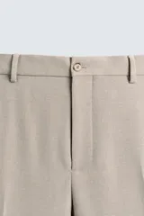 Pantalón de vestir color beige, corte slim fit, con bolsillos laterales y traseros con doble vivo y botón. Cierre frontal con cremallera y botón.