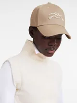 Gorra de béisbol color crema con logo bordado en verde en el frente.