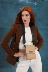 Bandolera tipo phone bag pequeña, color marrón claro, con correa de galón regulable. Tiene un compartimento principal y un bolsillo adicional con tapa.