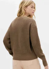Sweater tejido de punto color rosa, de corte holgado y cuello redondo.