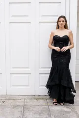 Vestido largo de fiesta color negro con lentejuelas, corte sirena, strapless con escote corazón y falda con volados.